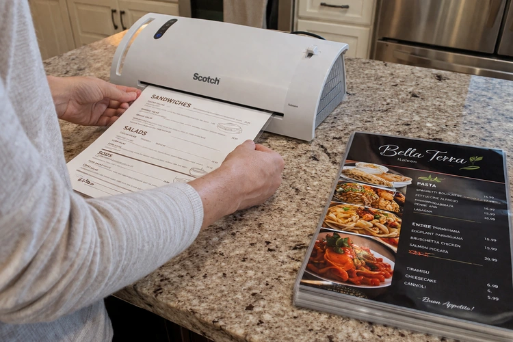 laminating restaurant menus at home with a pouch laminator on a desk